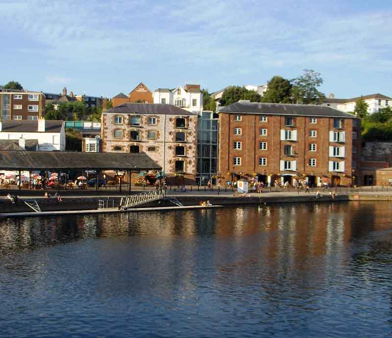 View from north bank of the River Exe of south quay side with shops and residential buildings.